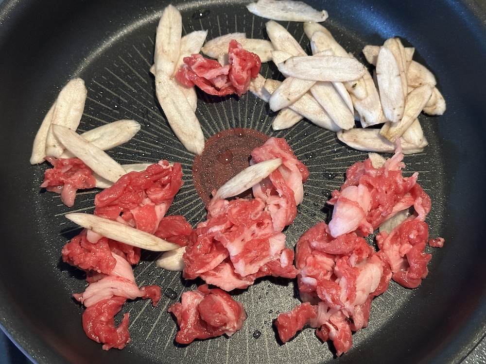 炒めている牛肉とごぼう